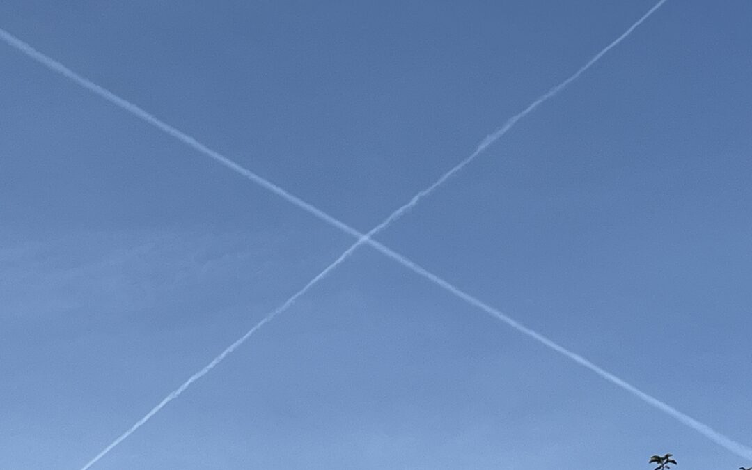 aus zwei Kondensstreifen von Flugzeugen entstandenes zartes weisses Kreuz auf blauem Himmel
